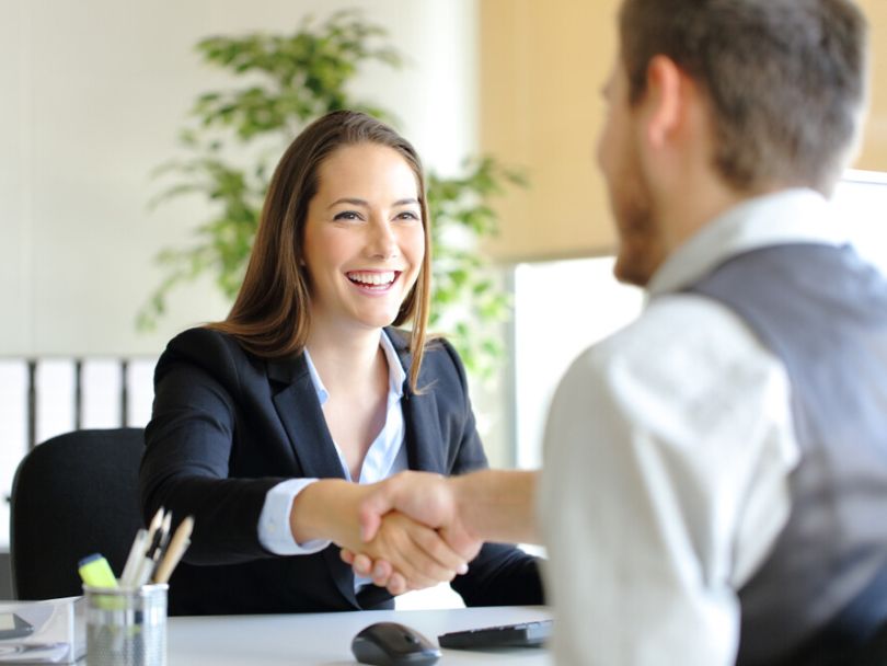 A professional woman shakes hands with a man representing her client